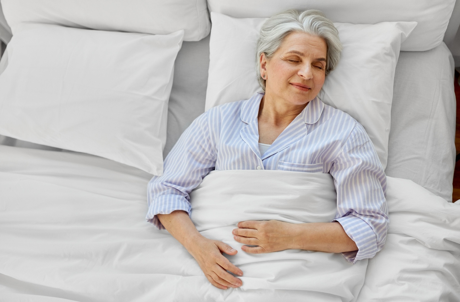 An older woman is sleeping in her bed during the day to offset sleep disruptions due to her dementia symptoms.