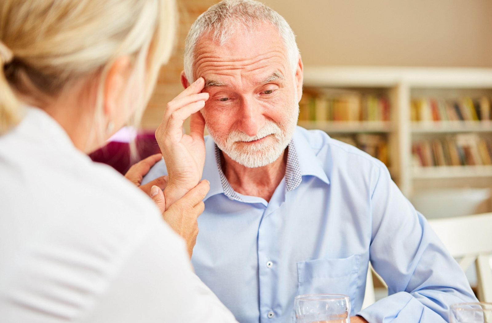 A senior with anxiety is comforted by their caregiver in a senior living community.