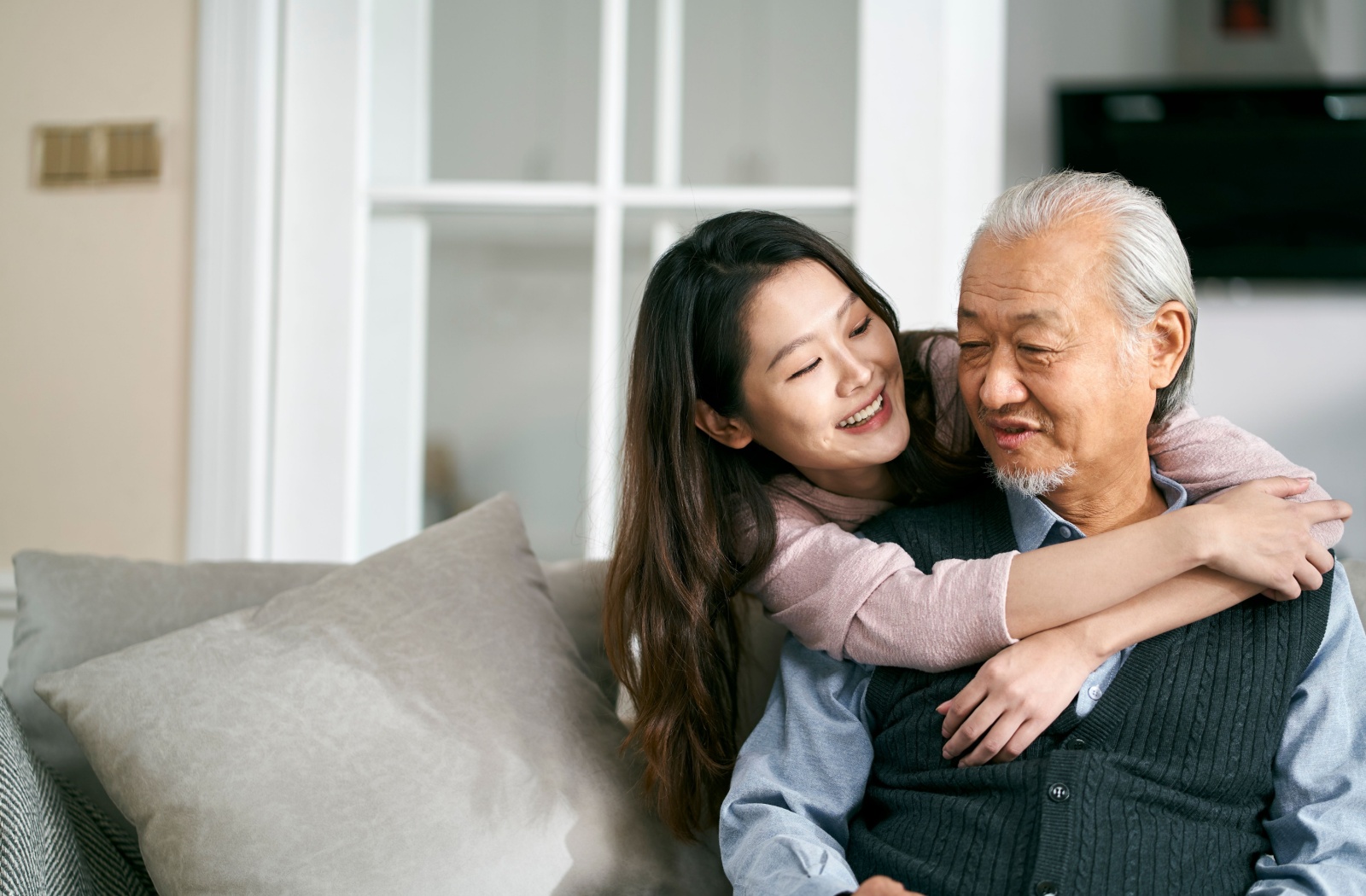 An adult child lovingly embraces their mature parent while in memory care.