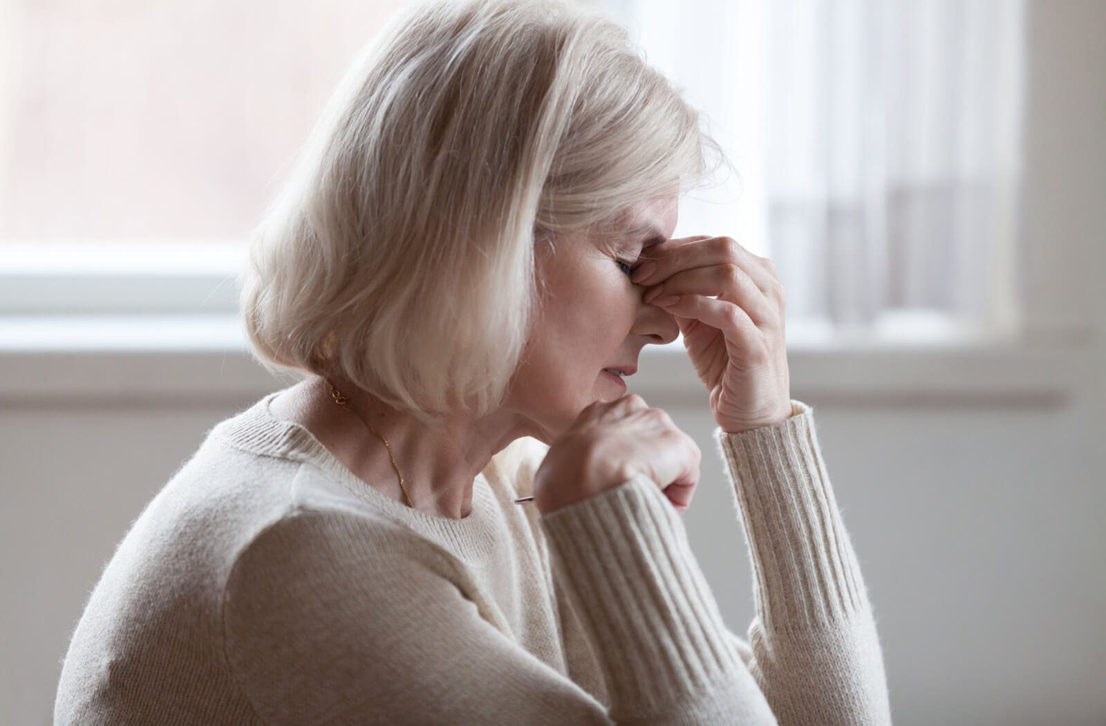 An older adult rubbing the bridge of their nose in frustration due to forgetfulness caused by dementia.
