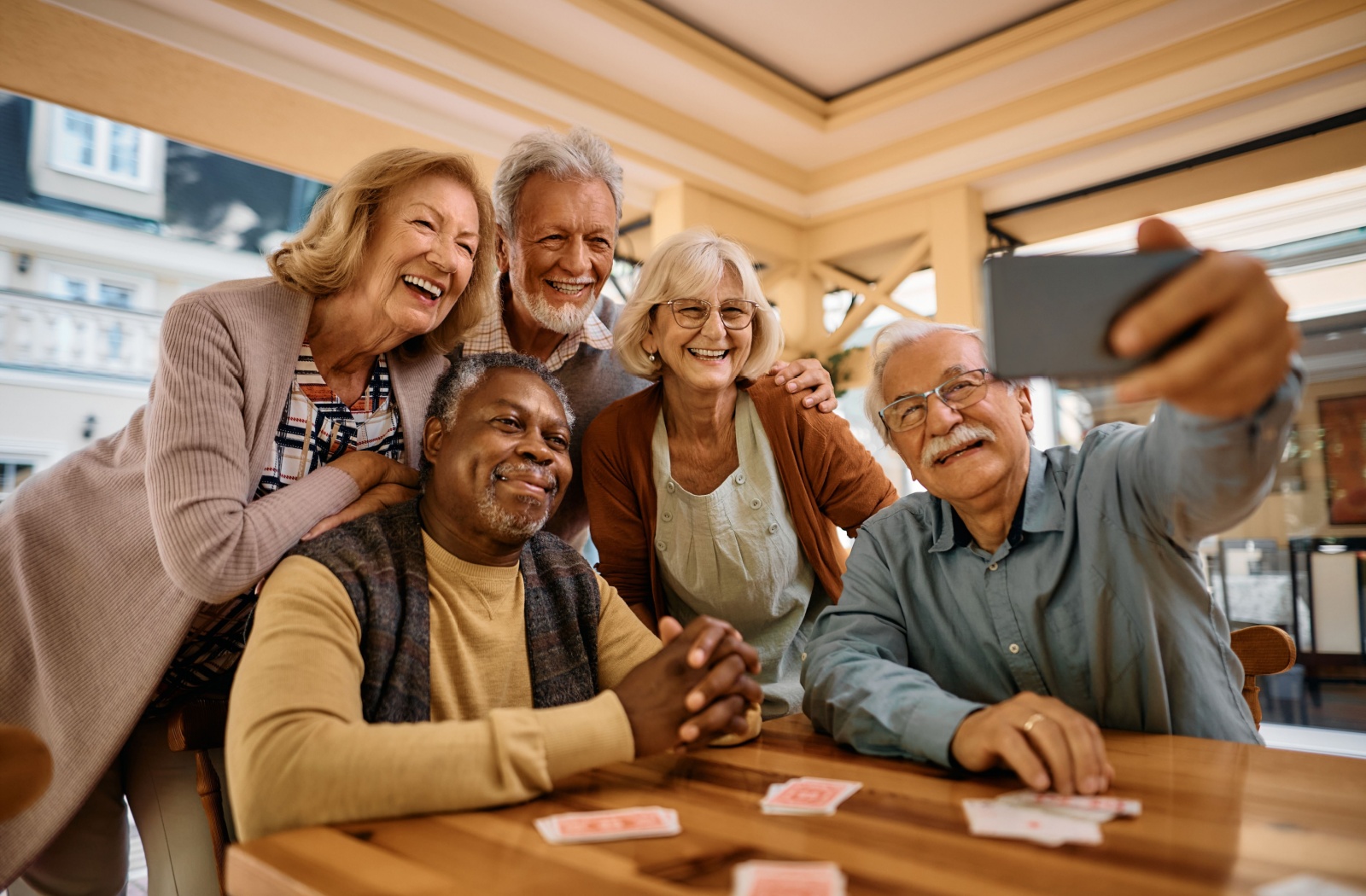 A group of smiling senior residents takes a group selfie.
