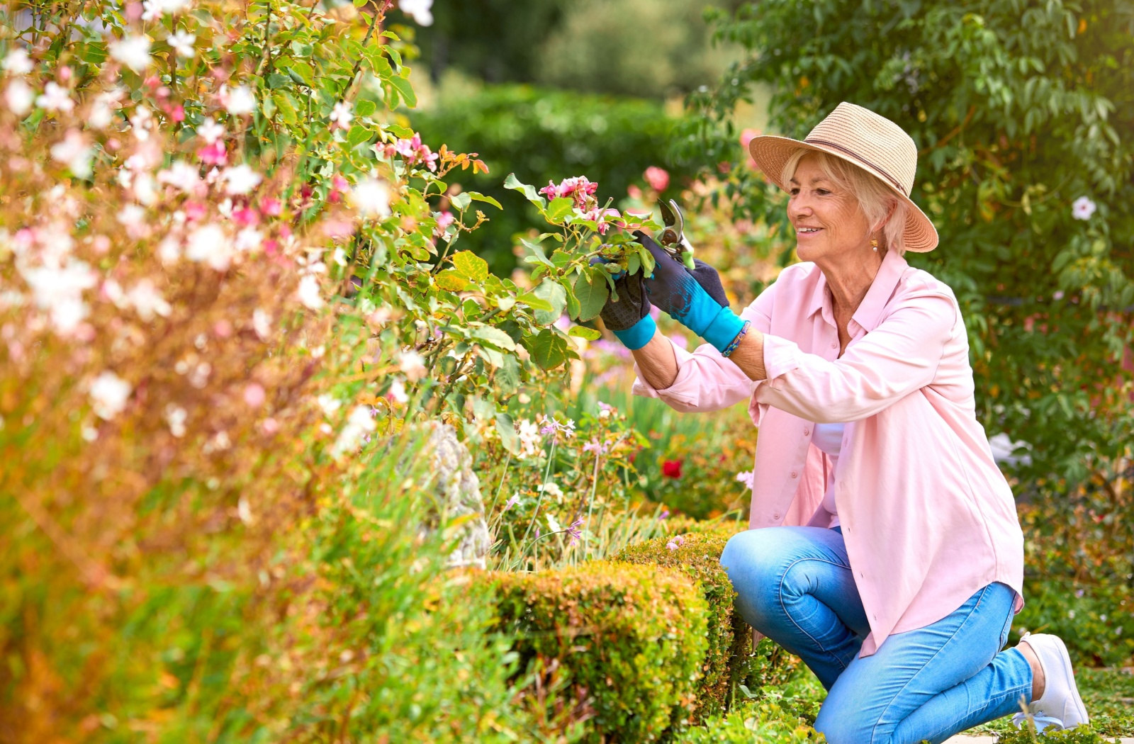 An older adult happily tends to flowers in a garden at a memory care community.