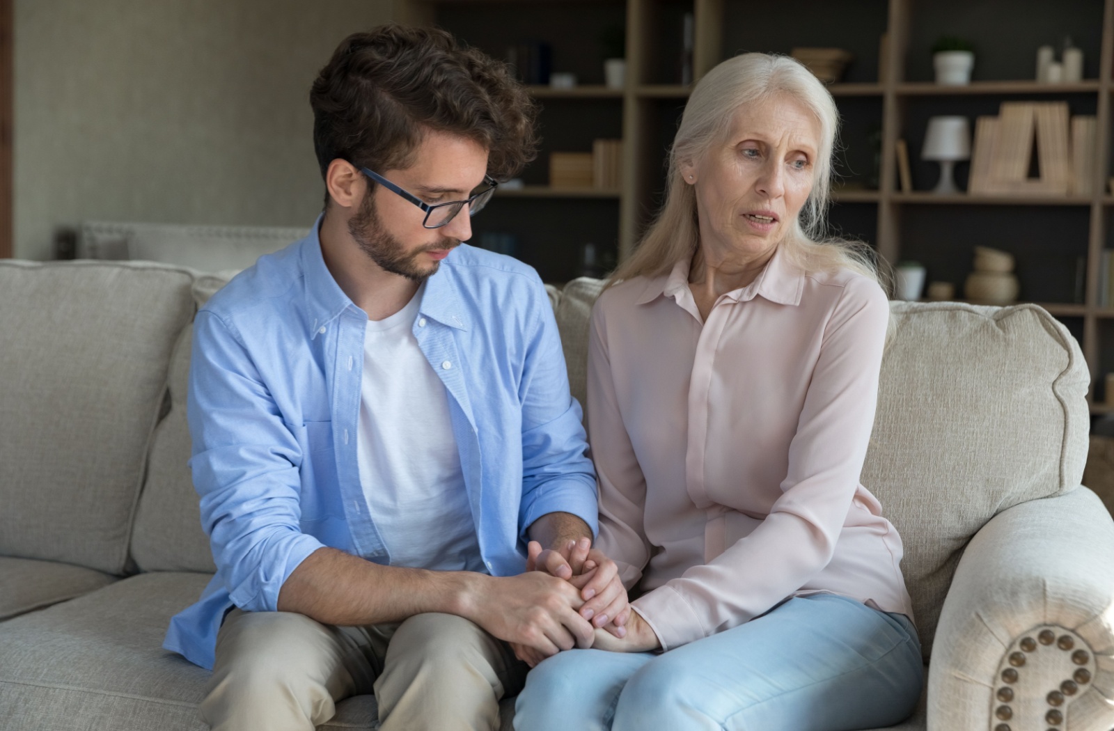 An adult comforts their parent with dementia, who looks upset.