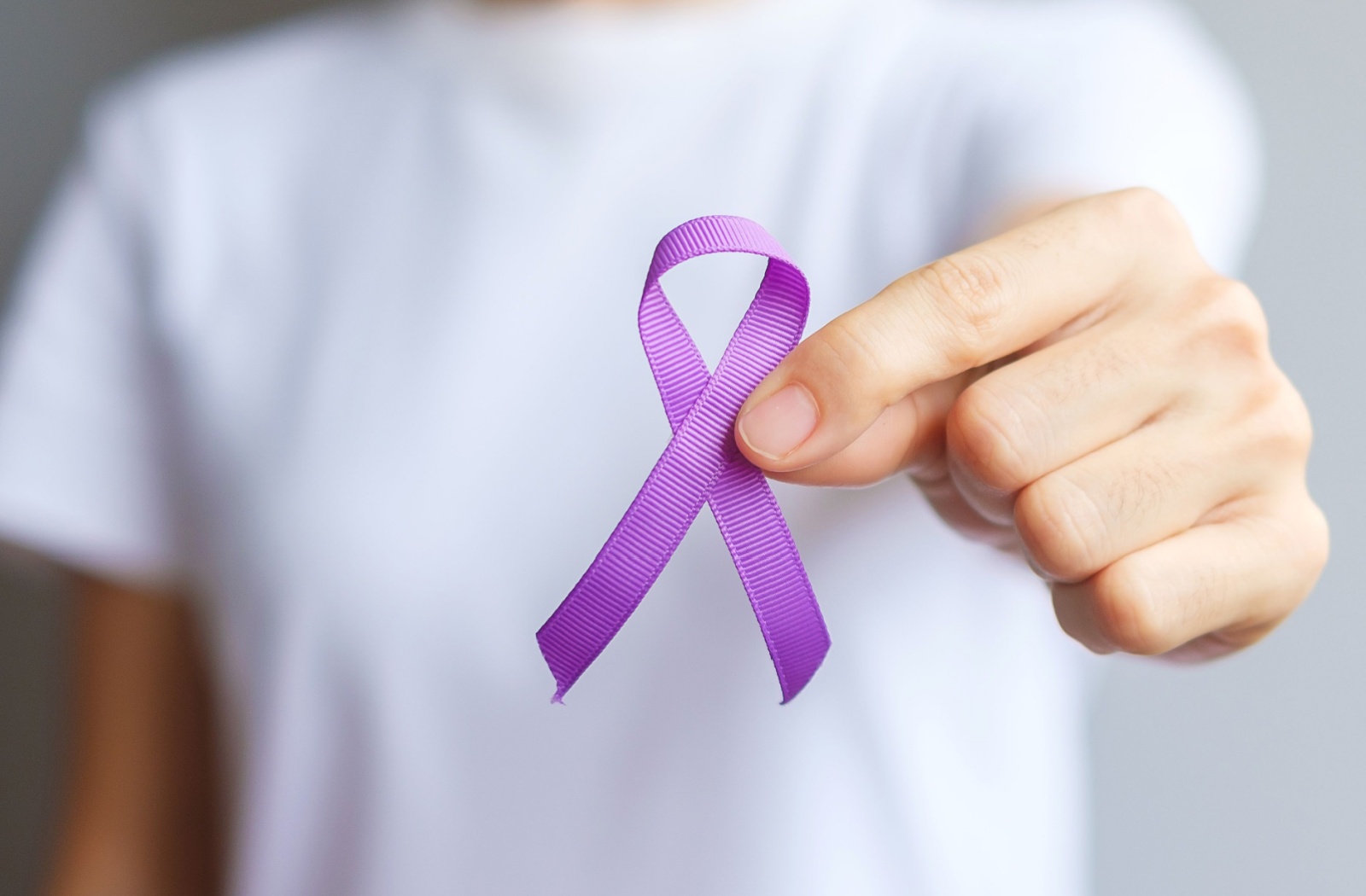A person in a white shirt holds out a purple ribbon, representing awareness of and research advocacy for dementia