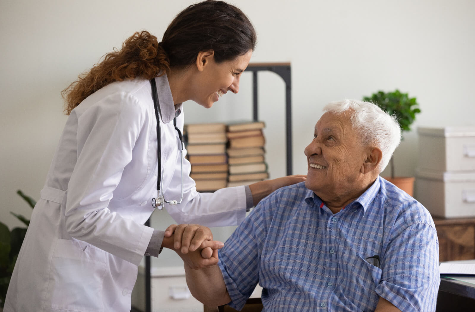 A doctor in memory care helping a resident with dementia prepare to stand after a health checkup.