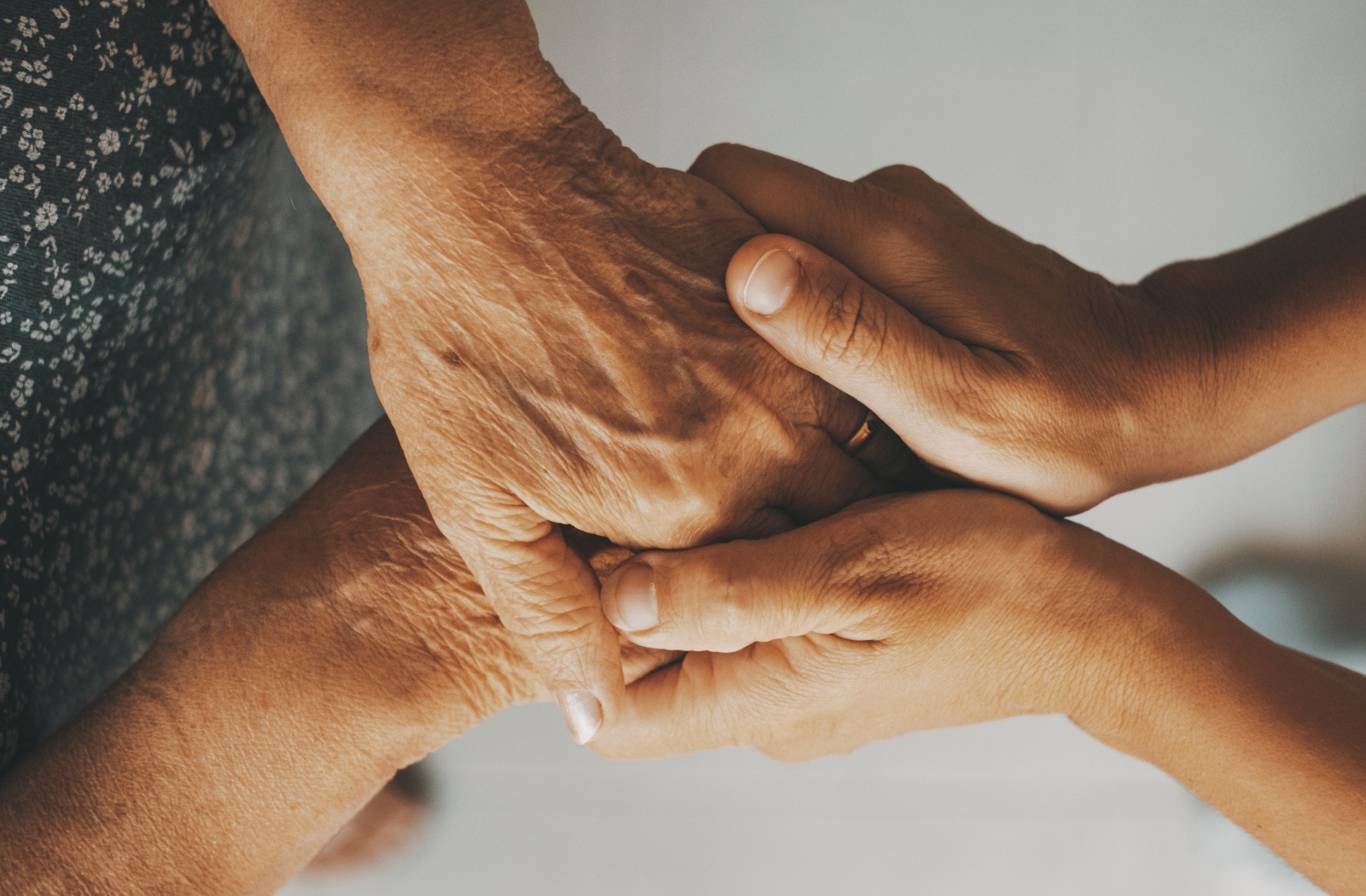 An adult child clasps their older parent's hands to reassure them about their recent cognitive changes and memory loss