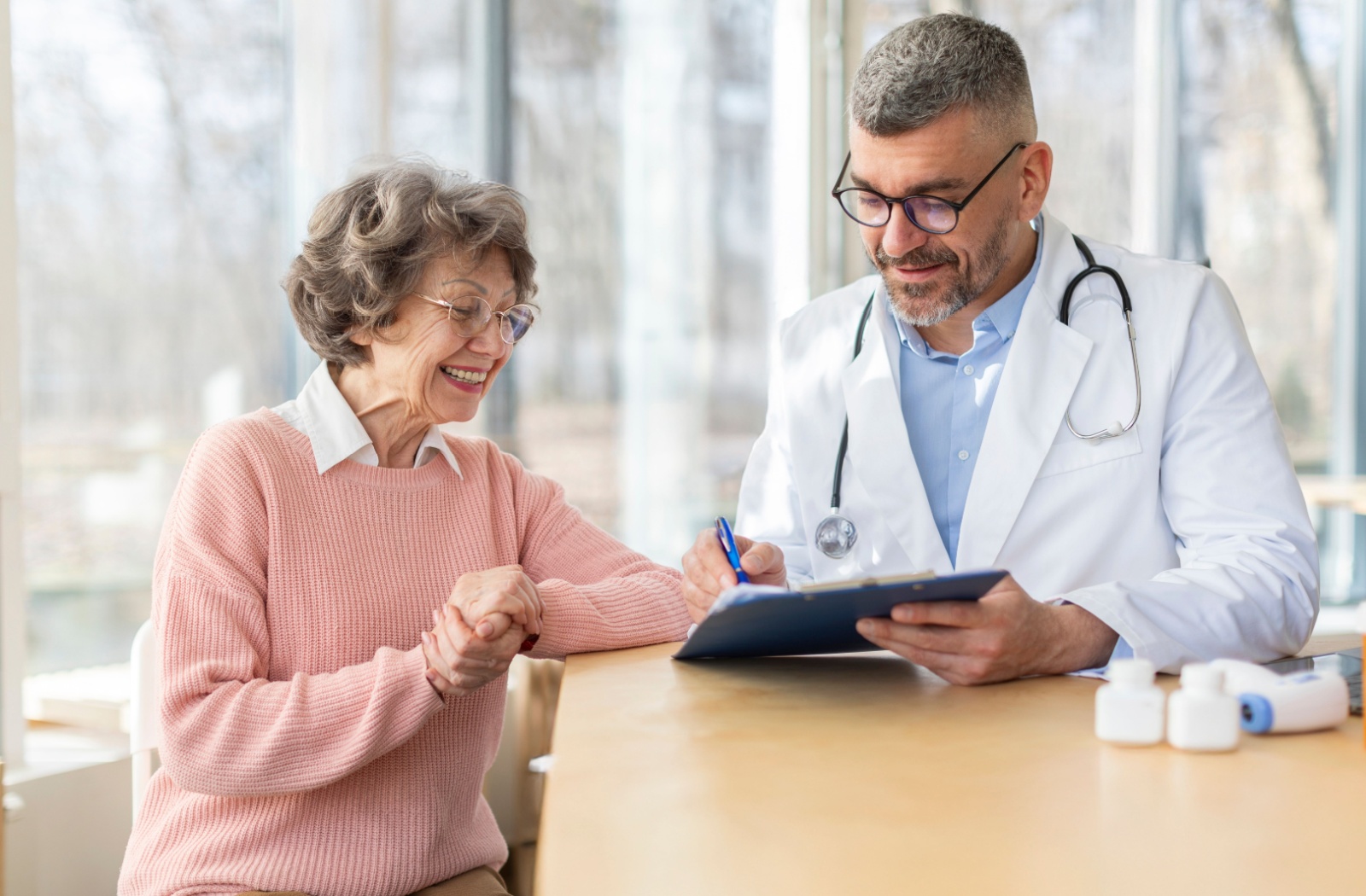 An older adult smiles while a doctor gestures to a tablet with a pen to show them the results of their FAST testing during a checkup